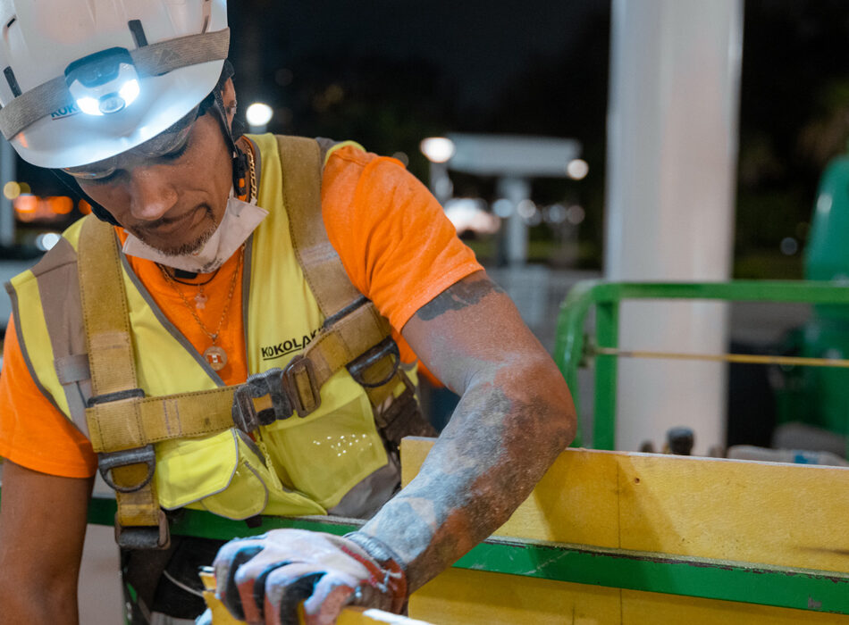 Dusty construction worker uses tool at night.