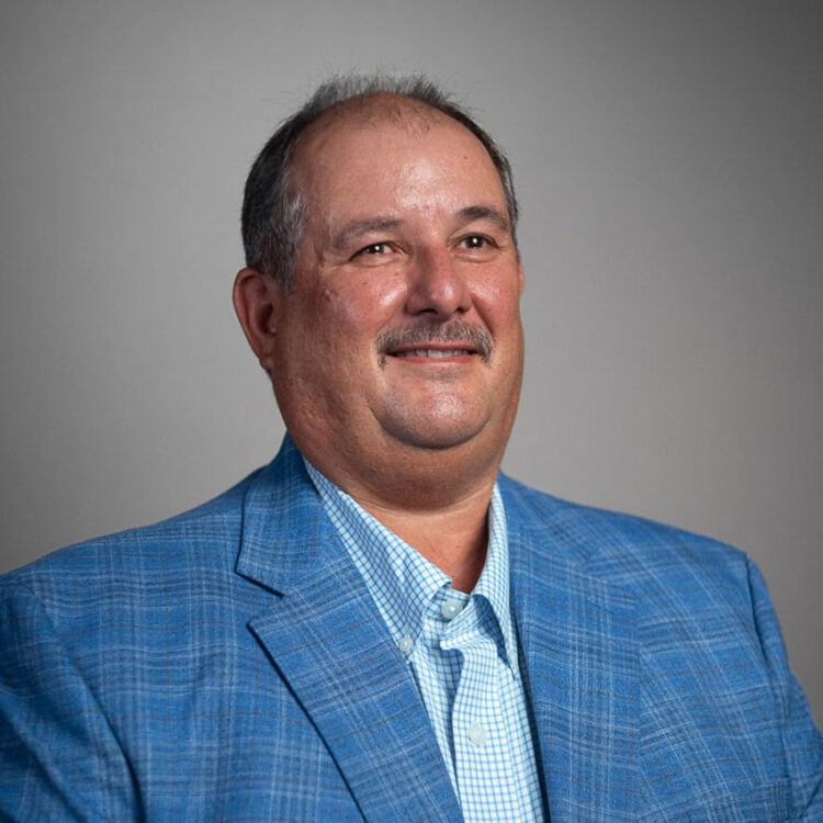 Smiling man in blue plaid suit and checked shirt.