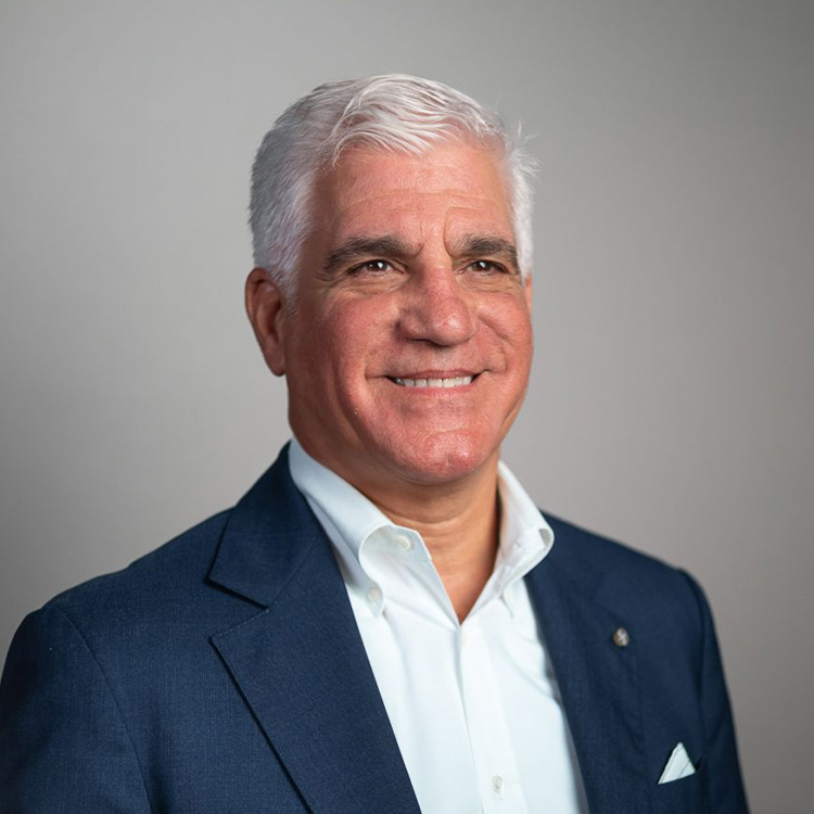 Smiling man in blue suit against gray background.