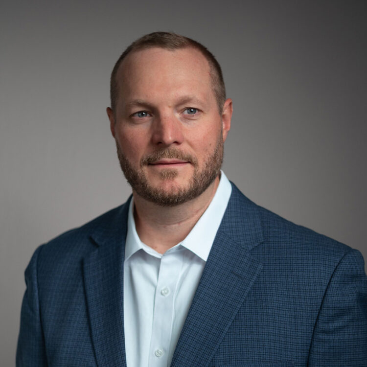 Man in blue checked suit jacket, looking sideways.