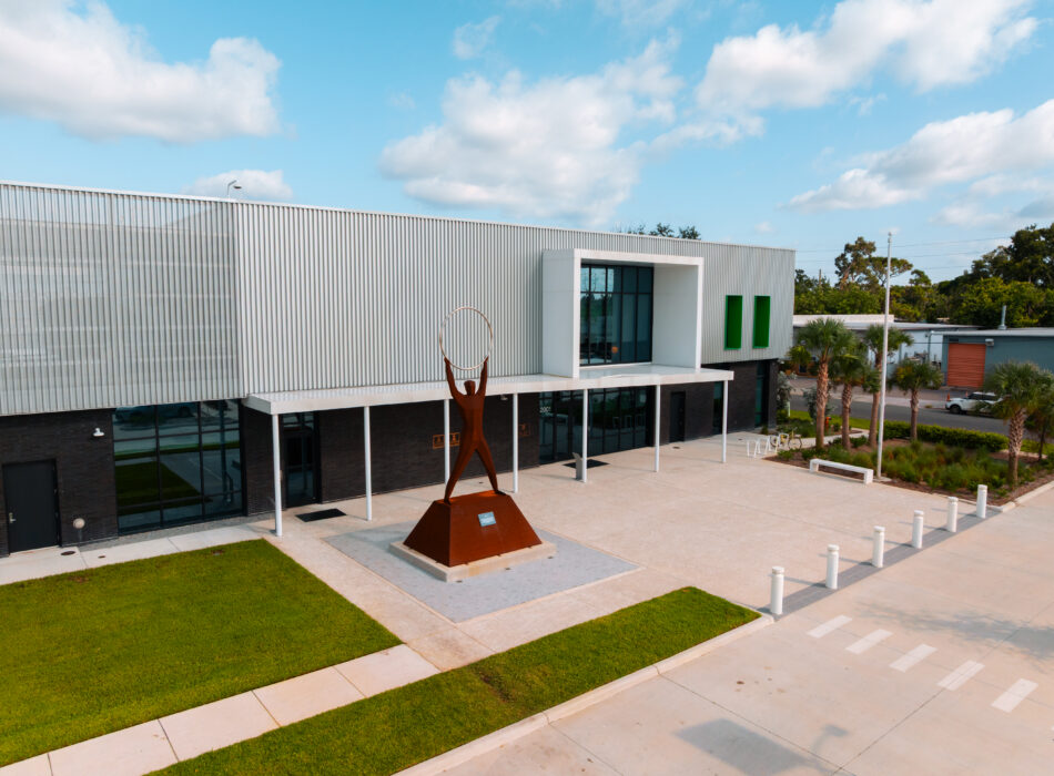 Modern building, lawn, and sculpture of figure with circle.