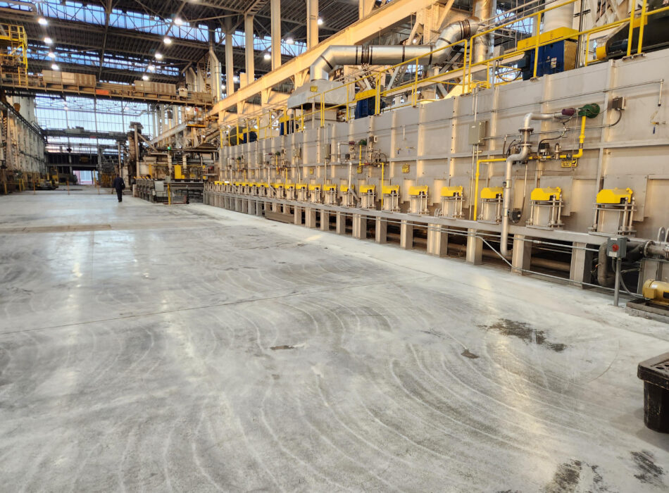 Factory interior with yellow machines, high ceilings, two people.