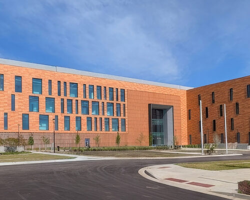 Modern orange-brick building with irregular windows and central entrance.