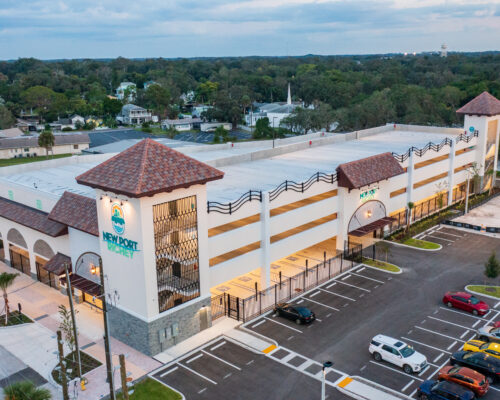 Mediterranean-style parking garage labeled NEW PORT, suburban setting.