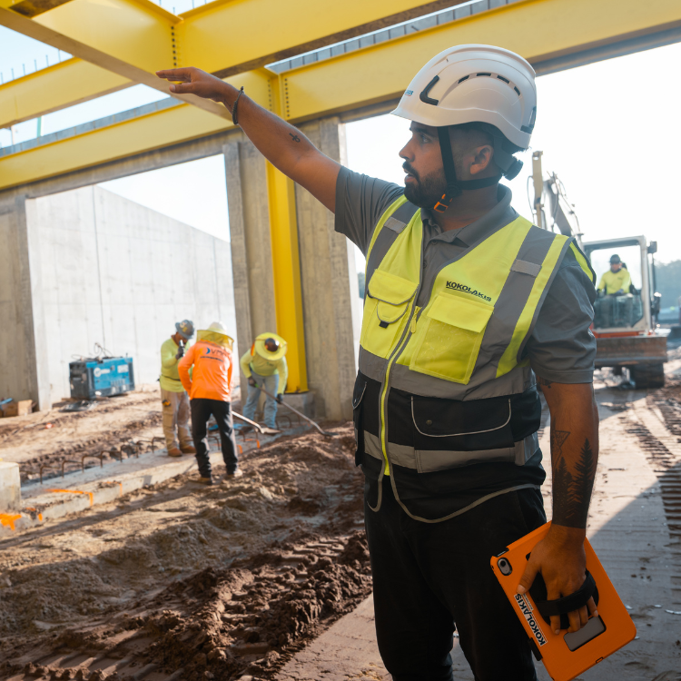 Construction worker gestures, others and equipment in unfinished building.
