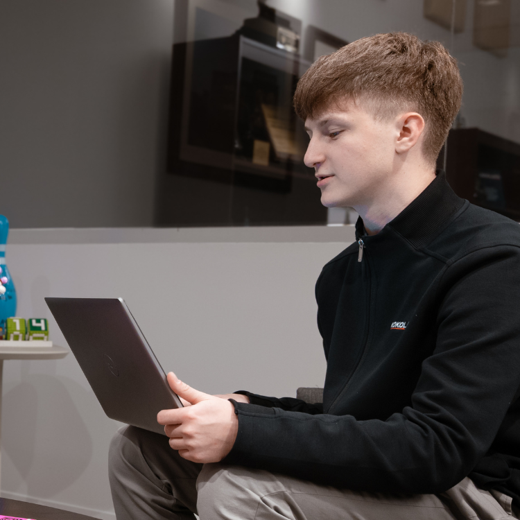 Young person with short brown hair using laptop indoors.