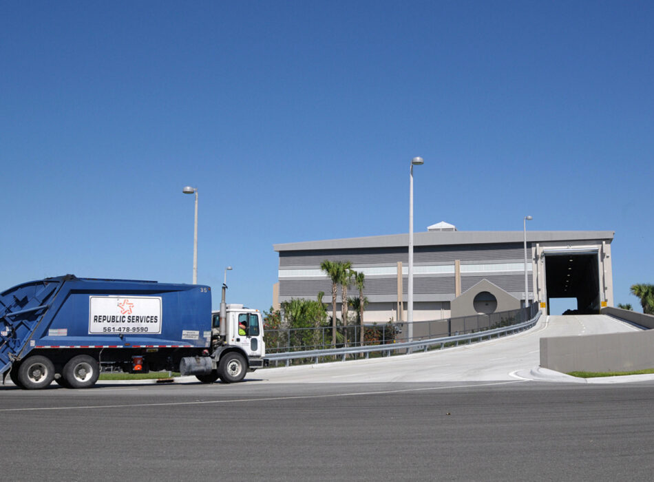 Blue Republic Services garbage truck by a modern building.