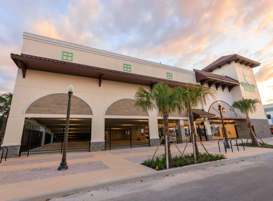 Beige parking garage with arches, palm trees, labeled tower.