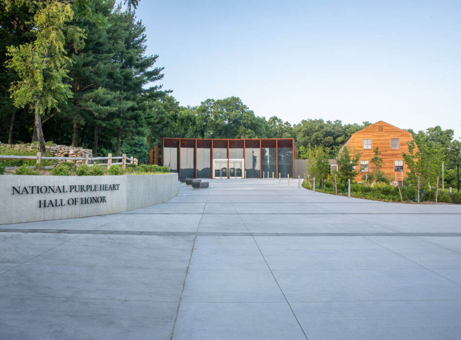 Hall of Honor entrance with flag, trees, and modern building.