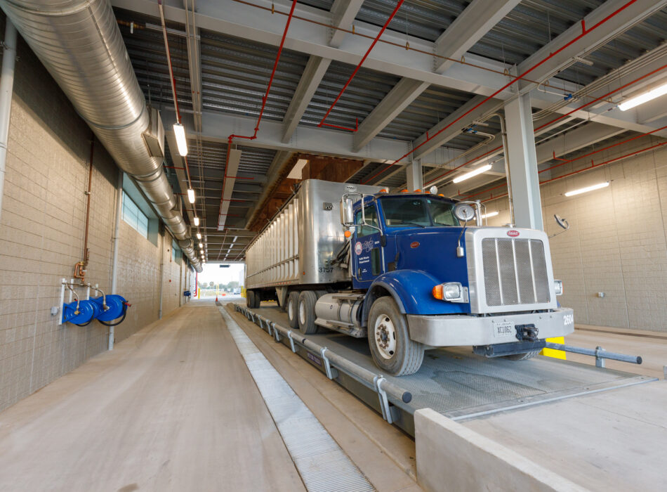 Blue semi-truck with trailer parked in industrial loading bay.