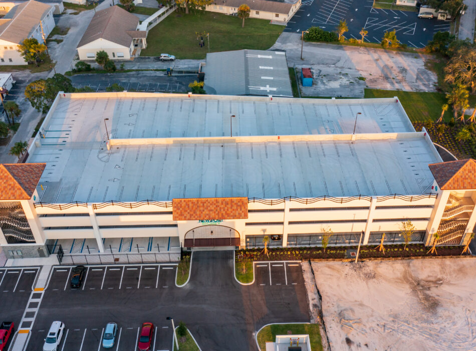 Aerial view of large building with orange roof and parking.