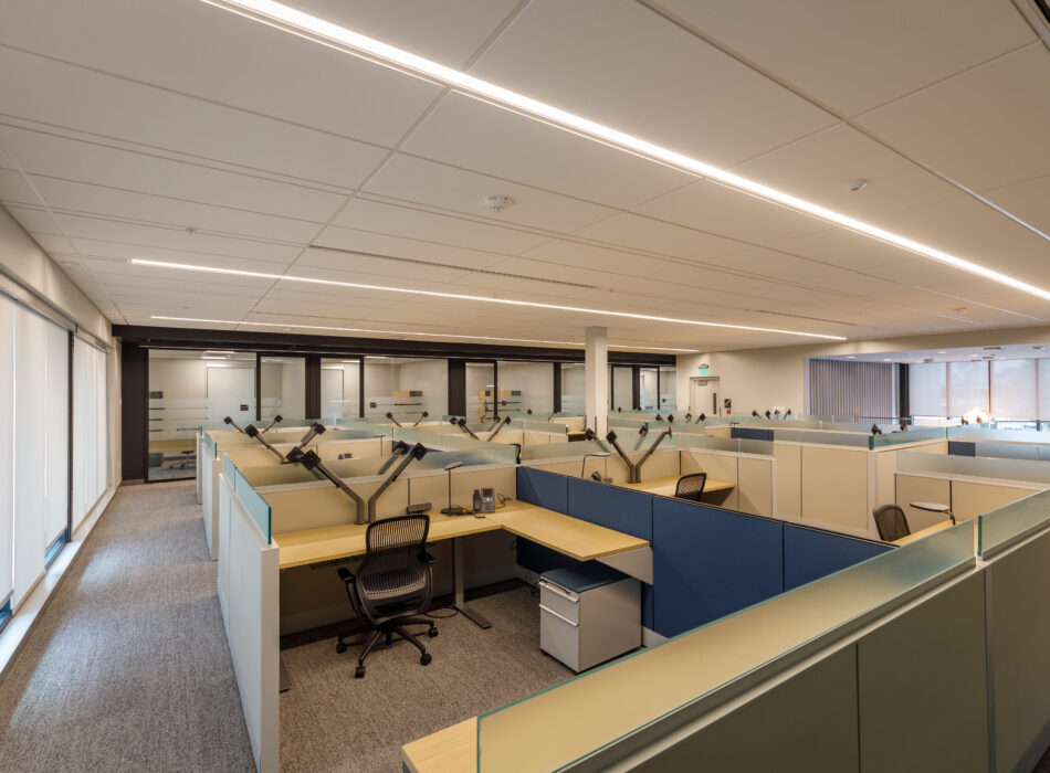 Modern office, empty cubicles, large windows, glass-walled rooms.