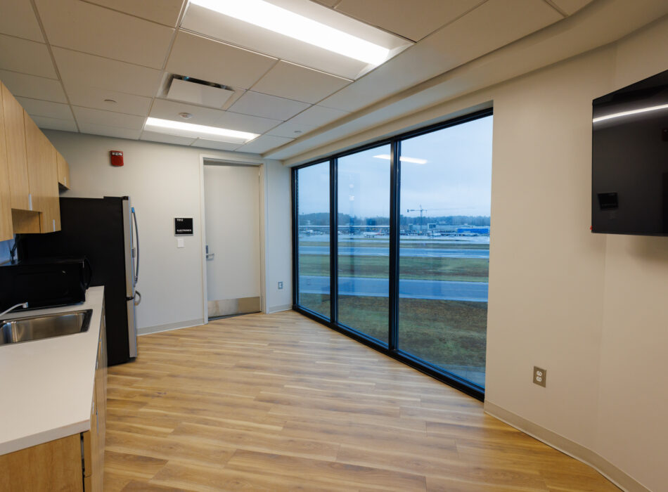 Break room with kitchenette, large windows, and outdoor view.