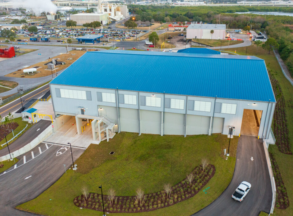 Blue-roofed industrial building, white vehicle, landscaped grounds.