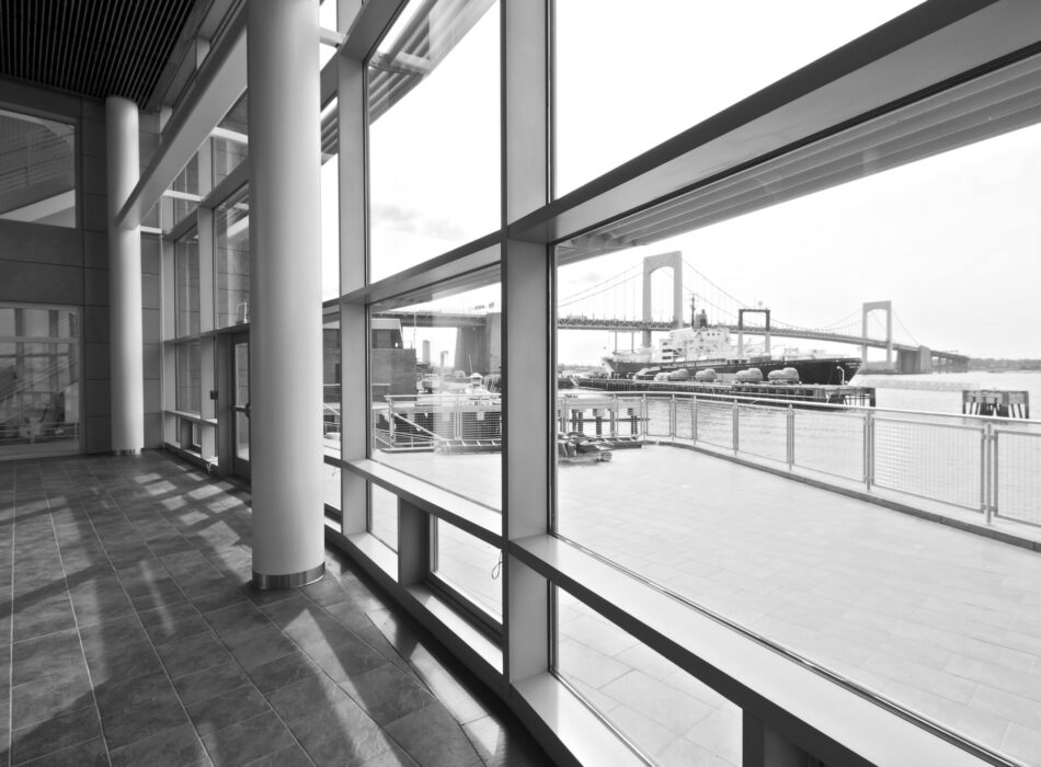 Modern interior with large windows facing river and bridge.