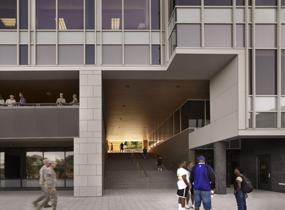 Modern building, people talking at entrance, others visible inside.