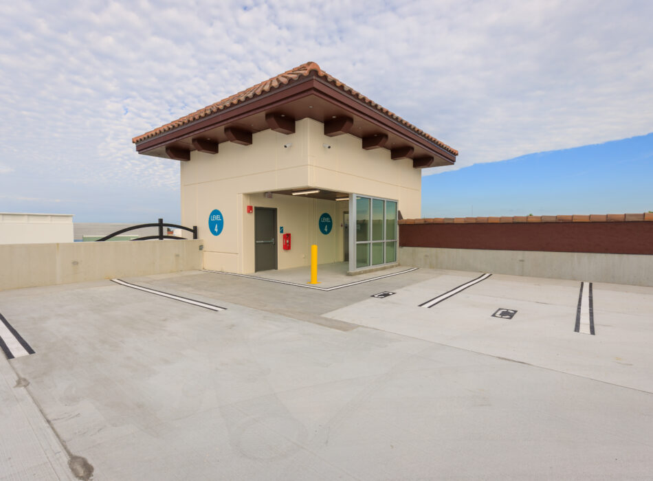 Rooftop parking, small building, glass door, blue elevator sign.