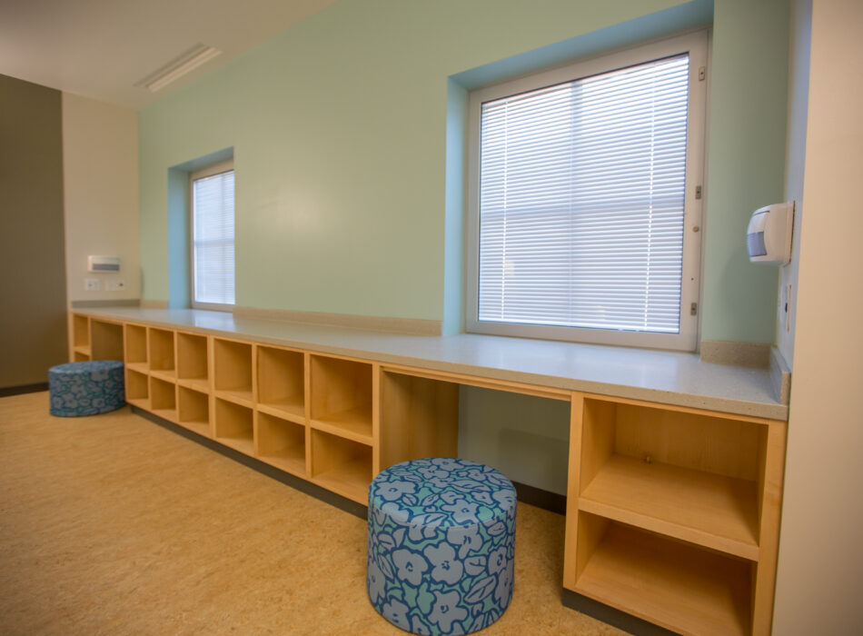 Room with two windows, counter, cubbies, and blue stools.