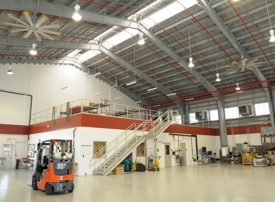 Forklift in large warehouse with mezzanine and equipment.