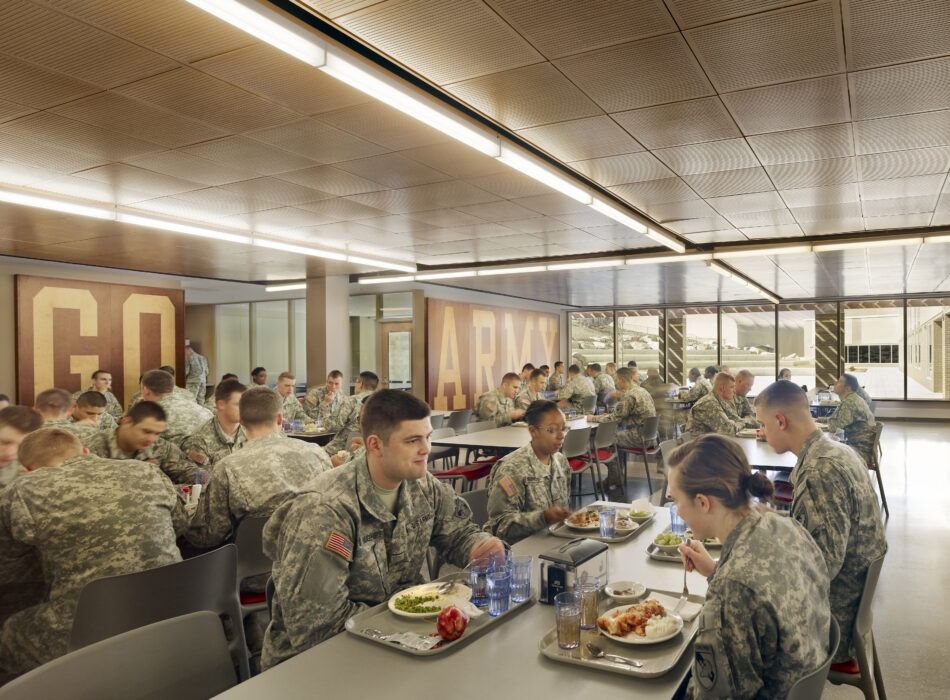 Soldiers eating and talking in cafeteria with GO ARMY sign.