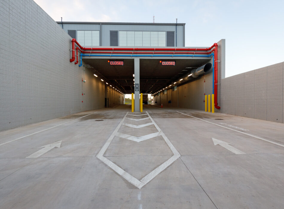 Closed drive-through lanes under building with pipes and arrows.