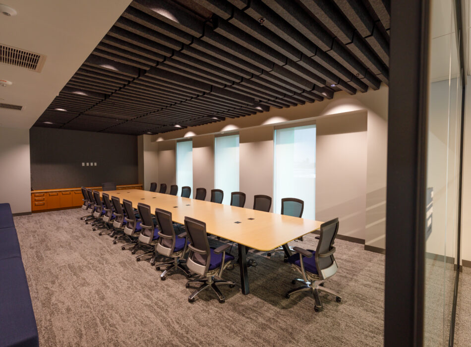 Conference room with long table, chairs, and frosted windows.