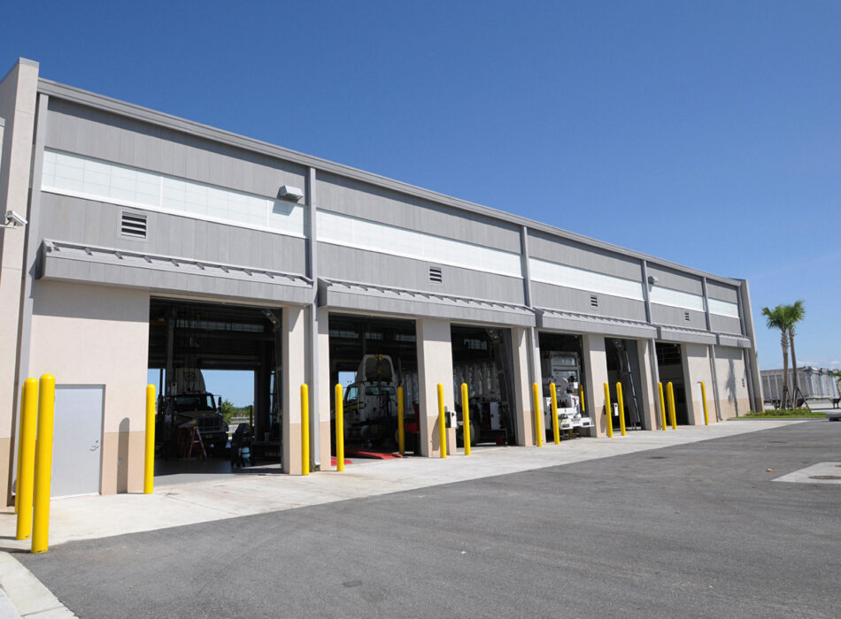 Modern vehicle facility with open bays, bollards, and vehicles.