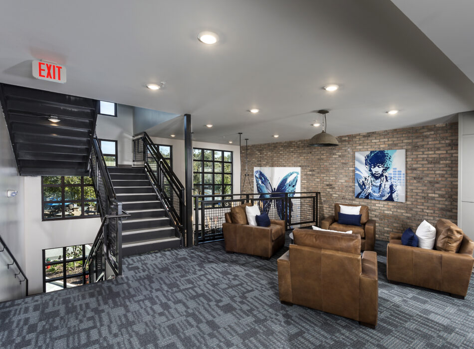 Modern lounge with leather chairs, blue carpet, brick wall.