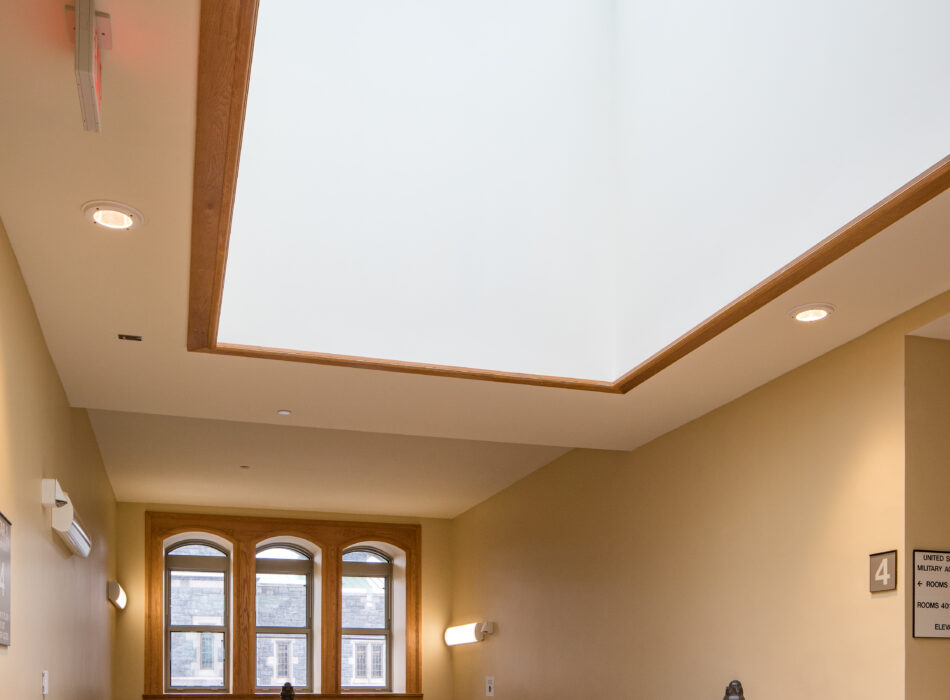 Hallway with skylight, beige walls, tile floor, staircase railing.