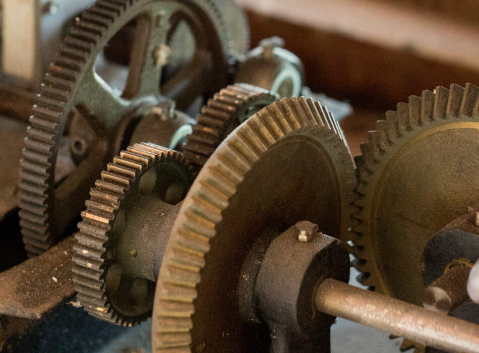 Interlocking metal gears with dust and wear.