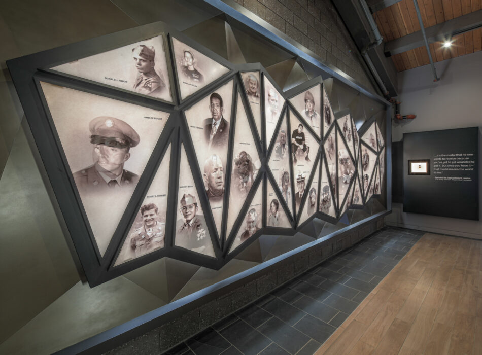 Portraits with names on a geometric museum display.