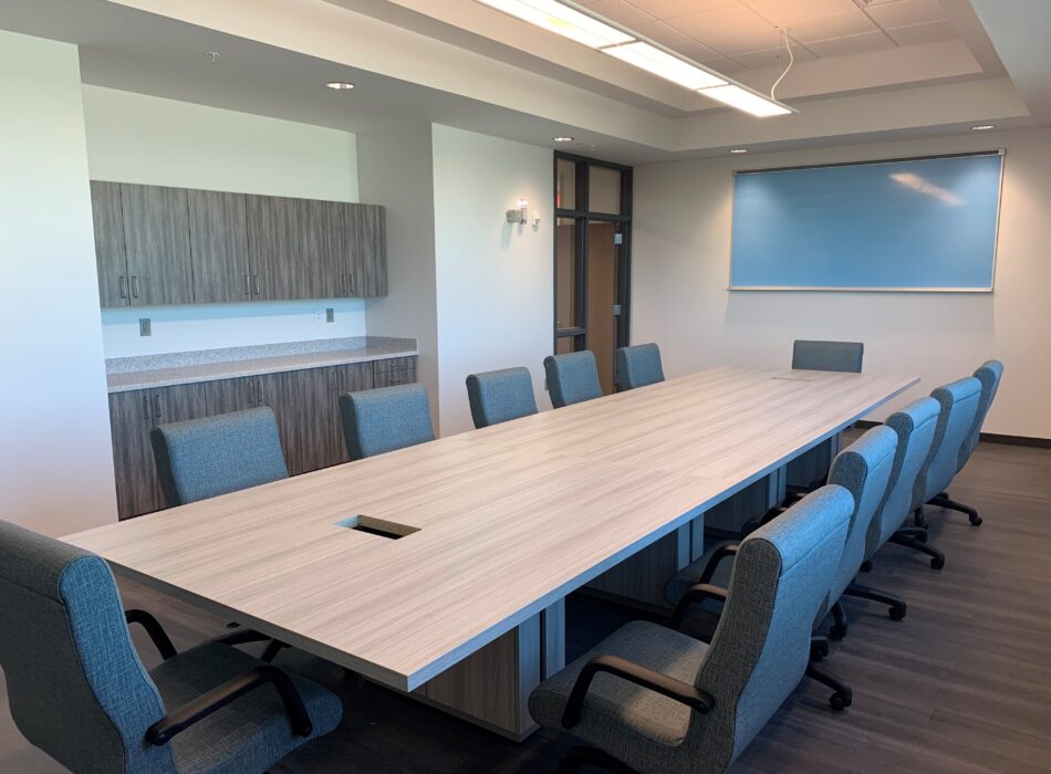 Modern conference room with table, chairs, cabinets, whiteboard.
