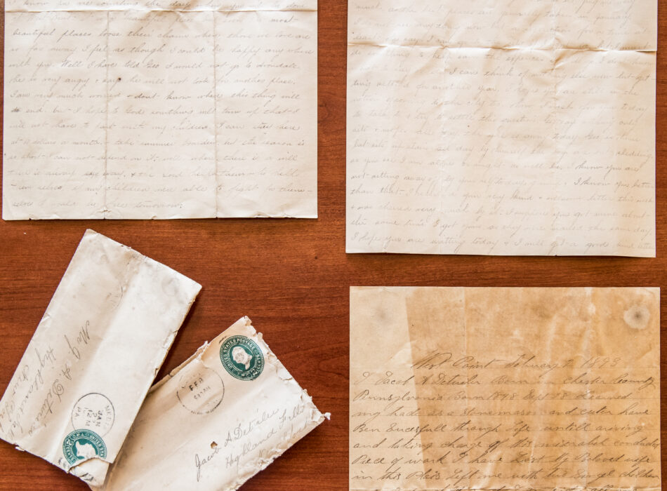Aged letters and envelopes with stamps on wood surface.