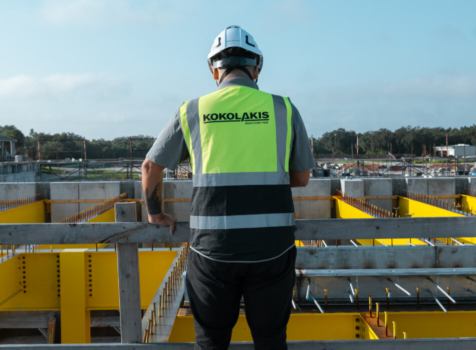 Worker in safety gear stands on platform, supervising site.