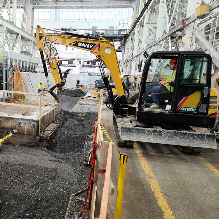 Worker uses small excavator to move gravel.
