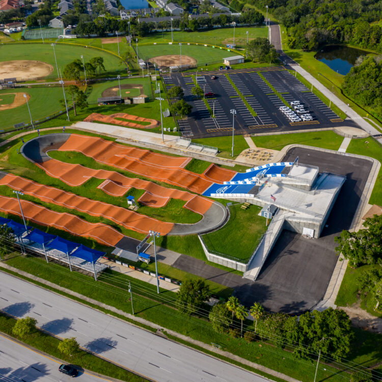 BMX track, modern building, parking lot, baseball fields, greenery.