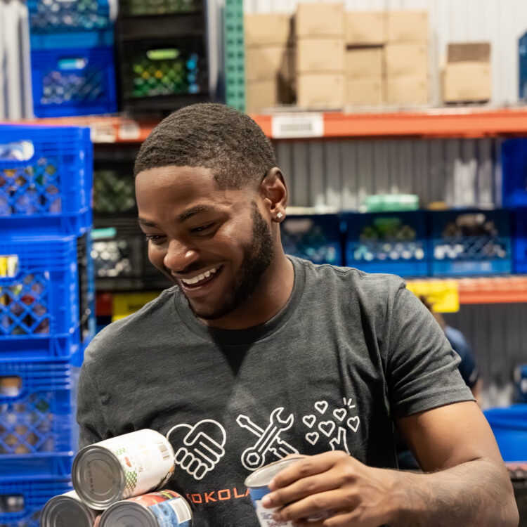 Smiling man organizes canned goods at food bank.