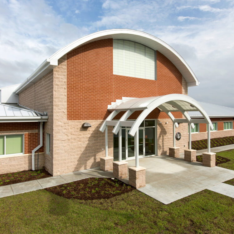 Modern brick building with curved canopy and large windows.