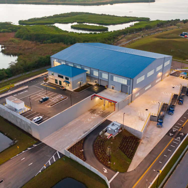 Aerial view of blue-roofed industrial facility near water.