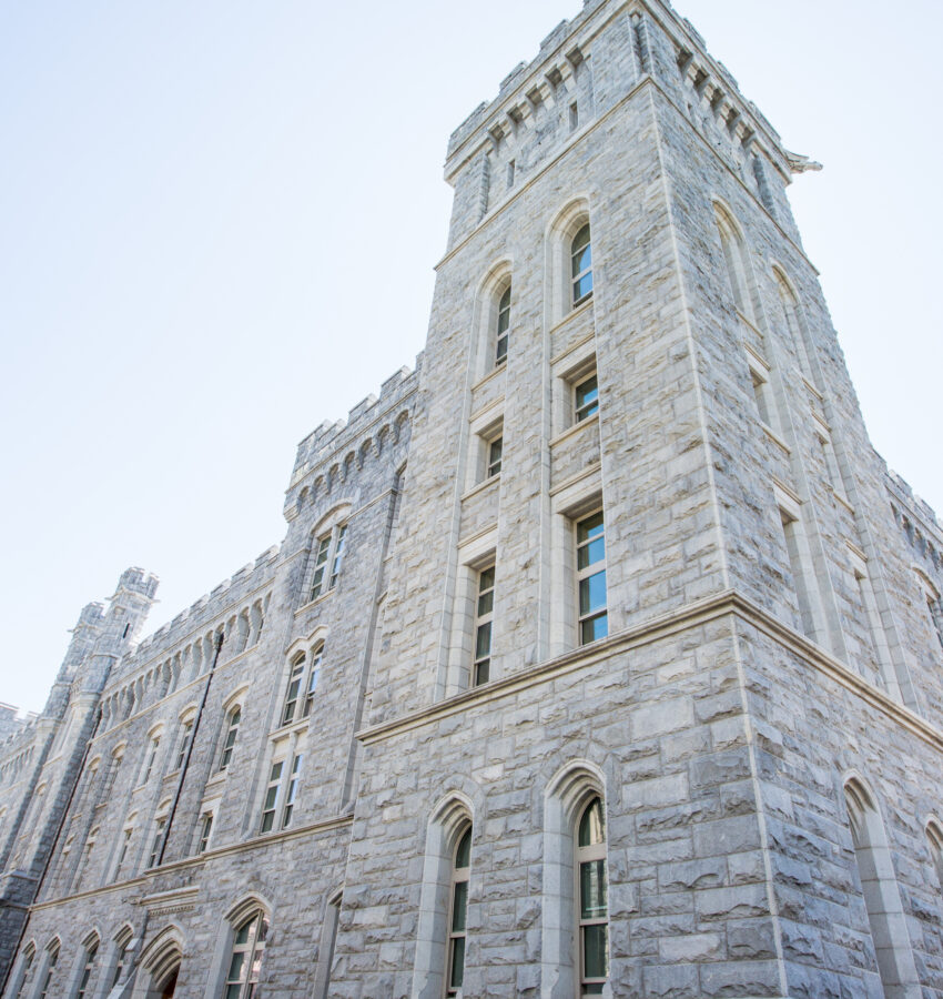 Tall stone building with arches and battlements against sky.